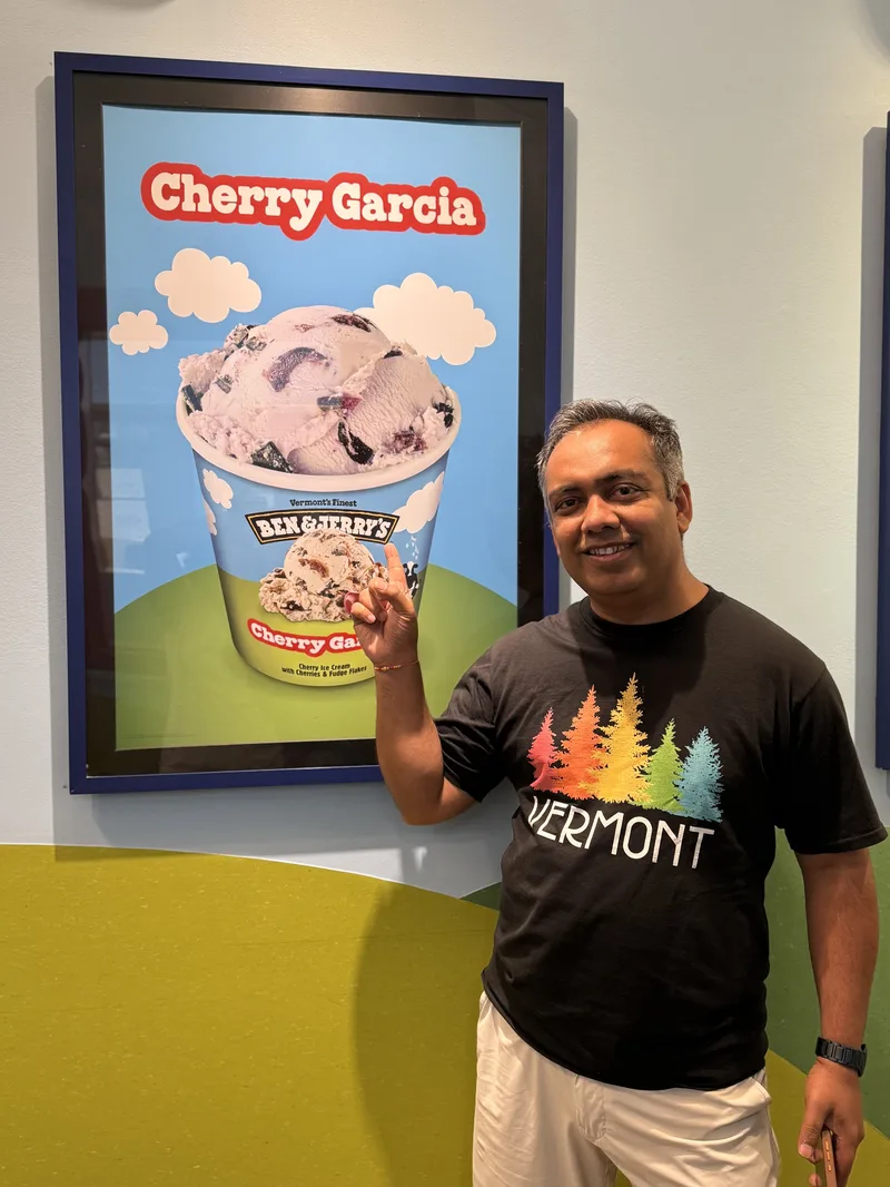 Jigar Desai at the Ben and Jerry's factory in Vermont, standing next to a Cherry Garcia poster