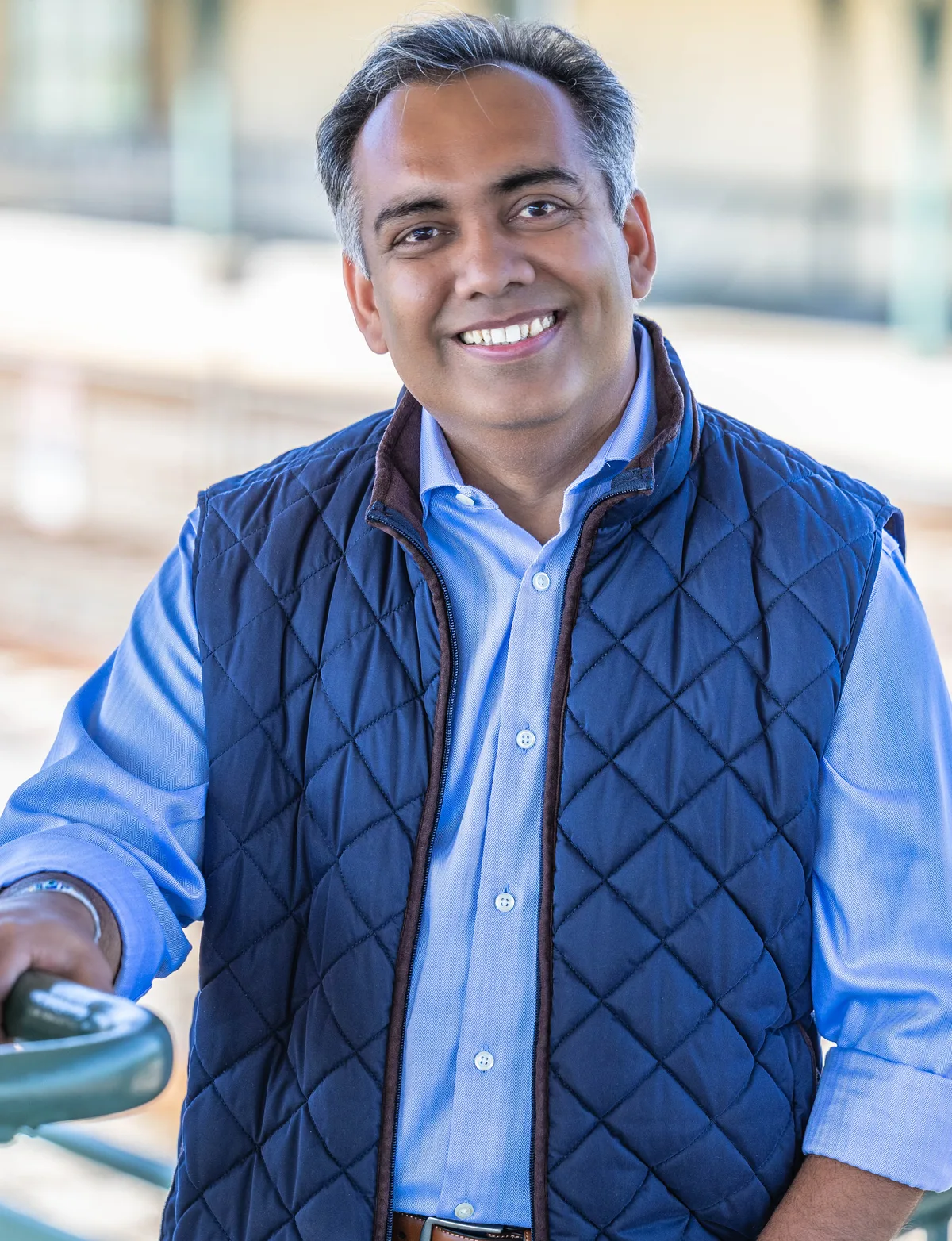 Jigar Desai leaning on a green railing at a train station